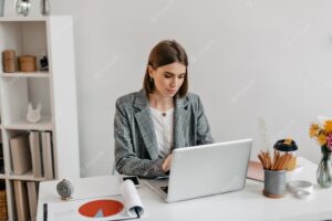 Business lady in gray jacket working in laptop. portrait of woman in office.