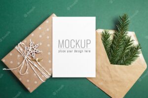 Christmas greeting card mockup with decorated gift box, envelope and green fir tree branch