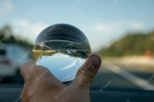 Closeup shot of a person holding a crystal ball with the reflection of trees