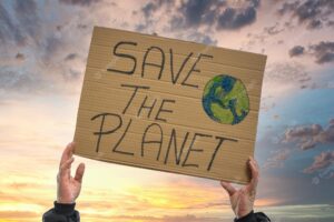 A closeup shot of a person holding a sign that says save the planet, on a sky background