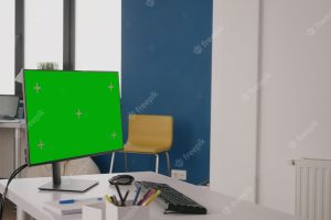 Company worker using green screen on computer at desk. woman working with isolated mock up template and chroma key on background. monitor with mock-up copy space on display in office.