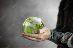 Earth day human hand holding a green world backed by leaves conservation and environment concept