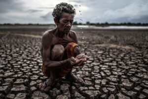 An elderly man sitting in touch with rain in the dry season, global warming, selection focus