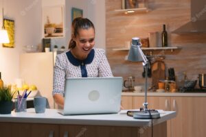 Excited woman feel ecstatic reading great online news on laptop working from home kitchen. happy employee using modern technology network wireless doing overtime studying writing, searching