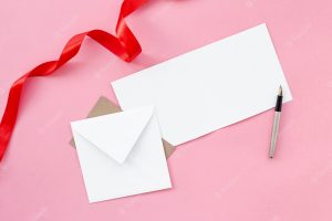 Flat lay of envelope with pen and ribbon