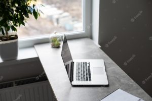 Gray workplace with laptop and large window