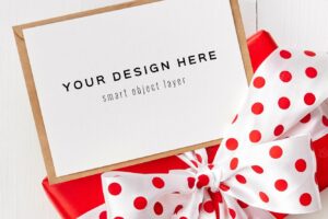Greeting card mockup with red gift box with bow on white background