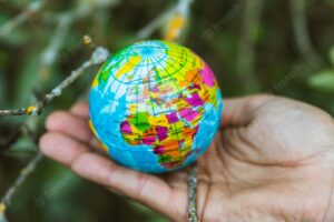 Hand holding small globe in nature