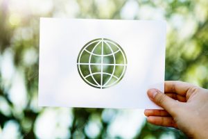 Hand showing perforated globe shape paper on green nature background