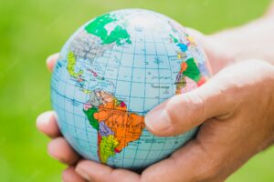 Hands holding small globe against green background