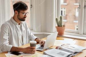 Image of concentrated unshaven businessman watches important webinar or online conference