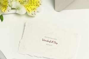 Invitation card on white background, bouquet flowers and grey envelope