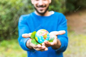 Male holding globe with green leaf and smiling