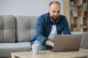 Man sitting on sofa and working from home on his laptop