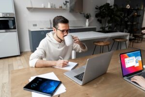 Man working from home at desk while having a drink