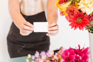 Midsection view of a female florist hand with blank white visiting card