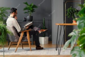 Modern man reading book while sitting in grey armchair in trendy