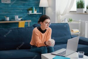 Person attending remote conversation on video call meeting, talking to teacher on teleconference for online class lesson. woman sitting on couch and using laptop with videoconference.