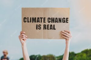 The phrase " climate change is real " drawn on a carton banner in men's hand. human holds a cardboard with an inscription: climate change is real