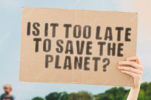 The question " is it too late to save the planet? " on a banner in men's hand with blurred background. climate change. pollution. global warming. cataclysms. environment. rubbish. co2