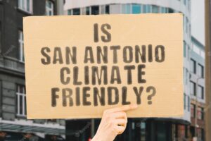 The question is san antonio climatefriendly is on a banner in men's hands with blurred background support team activist urban sunset carbon ecology energy new clean warming waste