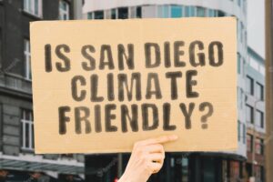 The question is san diego climatefriendly is on a banner in men's hands with blurred background support team activist urban sunset carbon ecology energy new clean warming waste