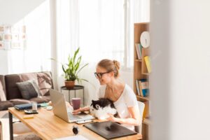 Side view of woman at desk with cat working from home