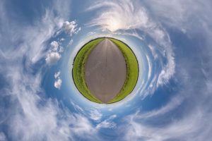 Tiny planet in blue sky with sun and beautiful clouds transformation of spherical panorama 360 degrees spherical abstract aerial view curvature of space