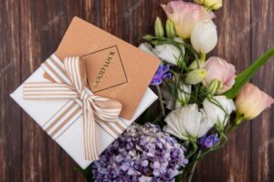 Top view of fresh flowers like gardenzia tulip roses with gift box isolated on a wooden background