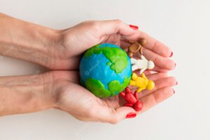 Top view of hands holding plasticine globe and people