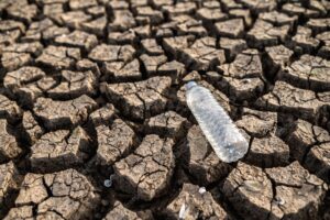 Water bottles on dry soil with dry and cracked soil, global warming