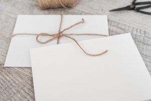 White envelopes with strings and scissor on wooden background