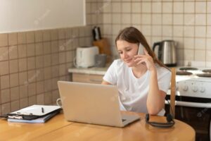 Woman working at home in the kitchen during quarantine on laptop