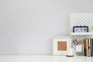 Workspace office supplies, coffee and photo frame on white creative table with copy space.