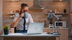 Business woman working from home late at night writing on laptop and drinking coffee. busy focused employee using modern technology network wireless doing overtime for job reading typing, searching