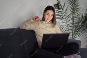 Caucasian woman using laptop while sitting on the sofa at home in the evening living room