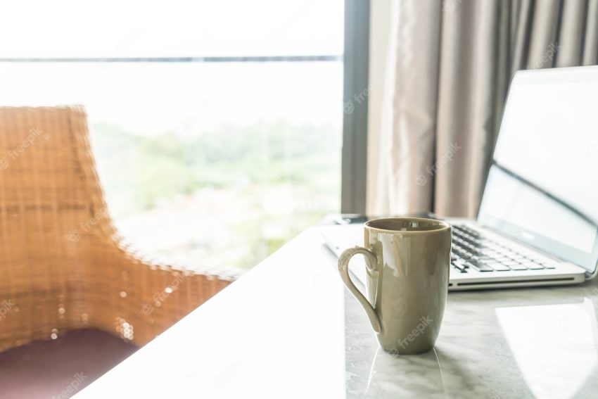 Coffee cup with laptop and beautiful luxury table decoration in livingroom interior for background