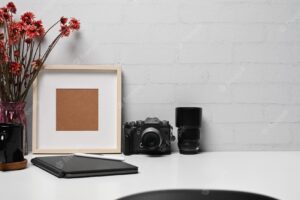 Photographer workplace with camera digital tablet coffee cup and picture frame on white table