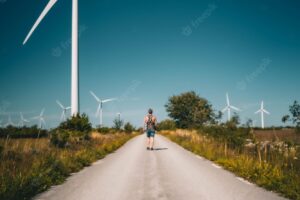 Vertical shot of a man walking on the road with windmill turbines on the roadsid